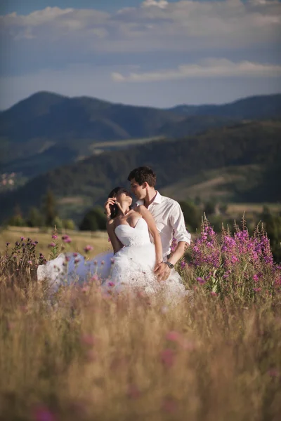 Casal de conto de fadas romântico recém-casados beijando e abraçando em um fundo de montanhas — Fotografia de Stock