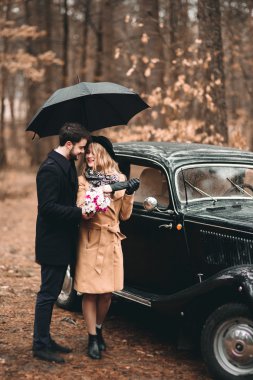 Romantik masal düğün çift öpüşme ve retro car yakınındaki çam ormanı içinde kucaklayan.