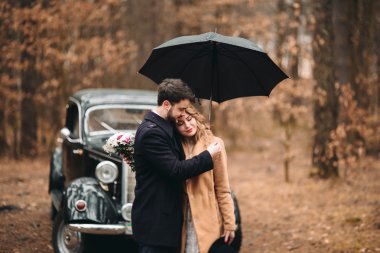 Romantik masal düğün çift öpüşme ve retro car yakınındaki çam ormanı içinde kucaklayan.