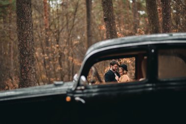 Romantik masal düğün çift öpüşme ve retro car yakınındaki çam ormanı içinde kucaklayan.