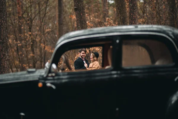 Romantisk saga bröllop par kyssar och omfamna i tallskogen nära retro bil. — Stockfoto
