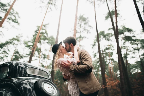 Romantik masal düğün çift öpüşme ve retro car yakınındaki çam ormanı içinde kucaklayan. — Stok fotoğraf