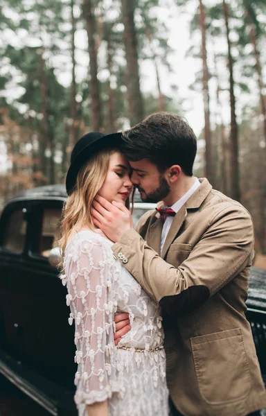 Romantico matrimonio da favola baciare e abbracciare nella pineta vicino auto retrò . — Foto Stock