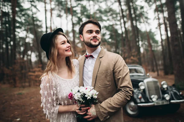 Romantico matrimonio da favola baciare e abbracciare nella pineta vicino auto retrò . — Foto Stock