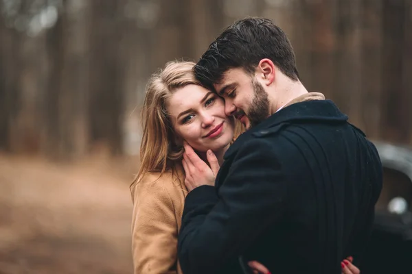 Casal de conto de fadas romântico casal beijando e abraçando na floresta de pinheiros perto de carro retro . — Fotografia de Stock