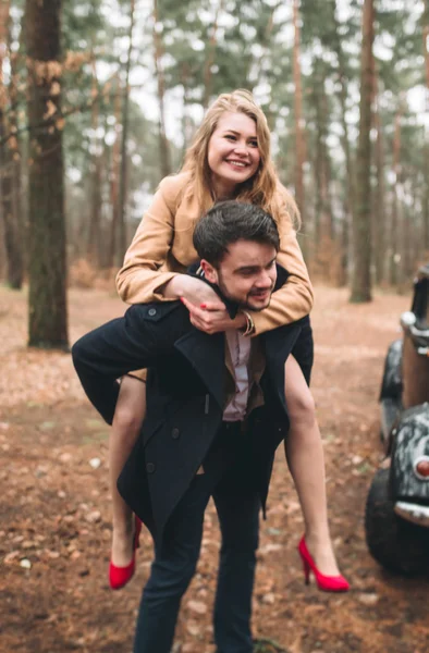 Romantic fairytale wedding couple kissing and embracing in pine forest near retro car. — Stock Photo, Image