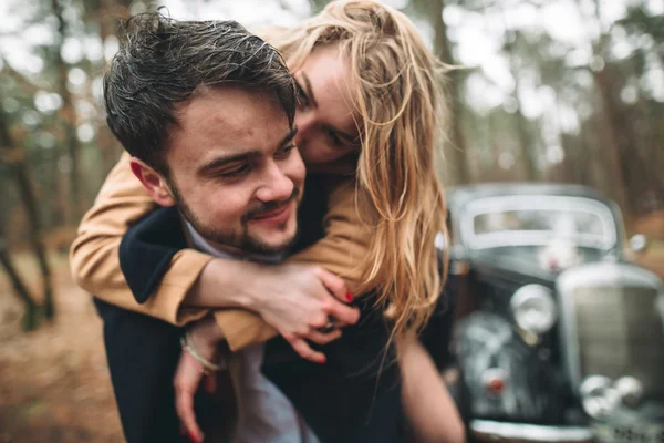 Romantik masal düğün çift öpüşme ve retro car yakınındaki çam ormanı içinde kucaklayan. — Stok fotoğraf