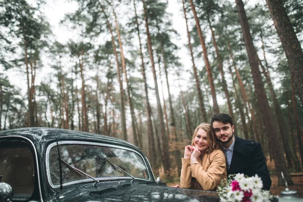 Romantico matrimonio da favola baciare e abbracciare nella pineta vicino auto retrò . — Foto Stock