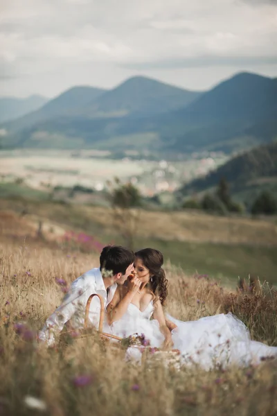 Casal bonito no piquenique com frutas e bolo em um fundo de montanhas — Fotografia de Stock