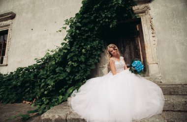 Güzel genç sarışın gelin gelin buketi arka plan güzel bitkiler merdivenlerde oturan ile