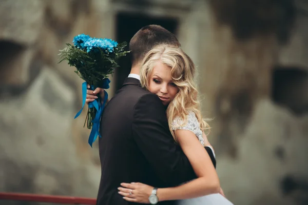 Feliz boda pareja abrazándose y sonriendo el uno al otro en el fondo viejo castillo — Foto de Stock