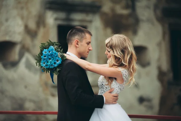 Glückliches Hochzeitspaar umarmt und lächelt sich auf alter Burg an — Stockfoto