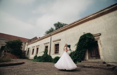 Güzel genç sarışın gelin gelin buketi arka plan güzel bitkiler üzerinde dans ile