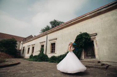 Güzel genç sarışın gelin gelin buketi arka plan güzel bitkiler üzerinde dans ile