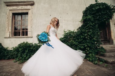 Güzel genç sarışın gelin gelin buketi arka plan güzel bitkiler üzerinde dans ile