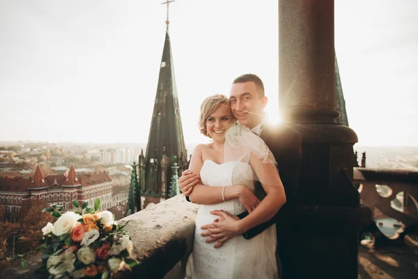 Stylový krásný svatební pár líbání a objímání na pozadí panoramatický výhled na staré město — Stock fotografie