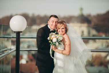 Güzel bir düğün çifti eski kasabanın arka plan panoramik manzarasında öpüşüp sarılıyor.