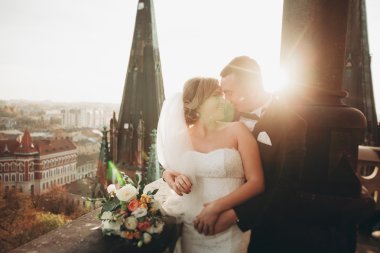 Güzel bir düğün çifti eski kasabanın arka plan panoramik manzarasında öpüşüp sarılıyor.