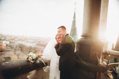 Güzel bir düğün çifti eski kasabanın arka plan panoramik manzarasında öpüşüp sarılıyor.