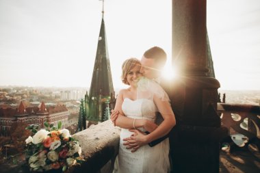 Güzel bir düğün çifti eski kasabanın arka plan panoramik manzarasında öpüşüp sarılıyor.