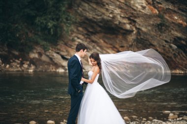 Zarif nazik şık damat ve gelin taşlarla Nehri yakınında. Evlilik çift aşık