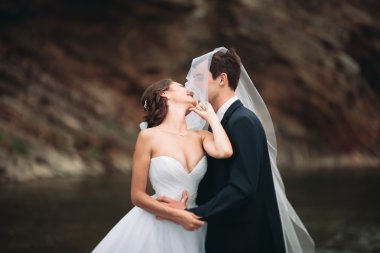 Zarif nazik şık damat ve gelin taşlarla Nehri yakınında. Evlilik çift aşık