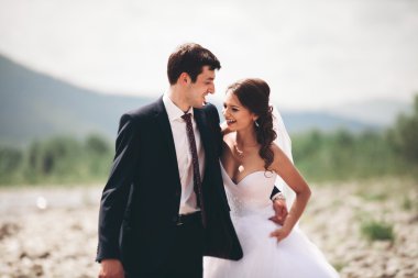 Zarif nazik şık damat ve gelin taşlarla Nehri yakınında. Evlilik çift aşık