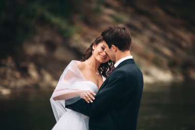 Zarif nazik şık damat ve gelin taşlarla Nehri yakınında. Evlilik çift aşık