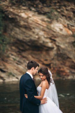 Zarif nazik şık damat ve gelin taşlarla Nehri yakınında. Evlilik çift aşık