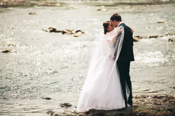 Elegante zachte stijlvolle bruid en bruidegom in de buurt van rivier met stenen. Bruidspaar in liefde — Stockfoto