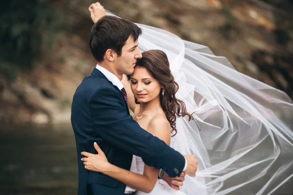 Elegantní jemný stylový ženich a nevěsta v blízkosti řeky s kameny. Svatební pár v lásce — Stock fotografie