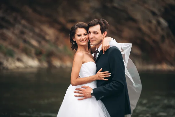 Elegante noivo elegante doce e noiva perto do rio com pedras. Casamento casal apaixonado — Fotografia de Stock