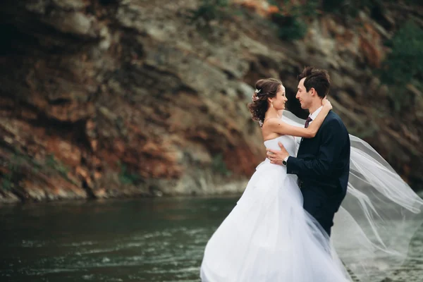 Élégant marié élégant doux et la mariée près de la rivière avec des pierres. Couple de mariage amoureux — Photo