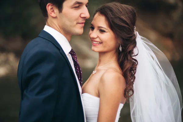 Elegante novio elegante y elegante novia cerca del río con piedras. Pareja de boda enamorada — Foto de Stock