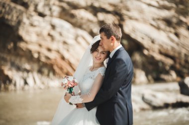 Yakışıklı romantik damat ve güzel gelin Nehri manzaralı dağlarında yakınında poz