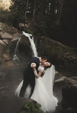 Güzel düğün çifti Nehri manzaralı dağlarda taş kalmak