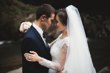 Güzel düğün çifti Nehri manzaralı dağlarda taş kalmak