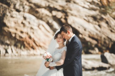 Yakışıklı romantik damat ve güzel gelin Nehri manzaralı dağlarında yakınında poz