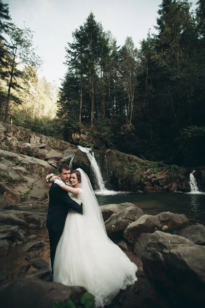 Όμορφο γαμήλιο ζεύγος μείνετε στην πέτρα του ποταμού στα γραφικά βουνά — Φωτογραφία Αρχείου
