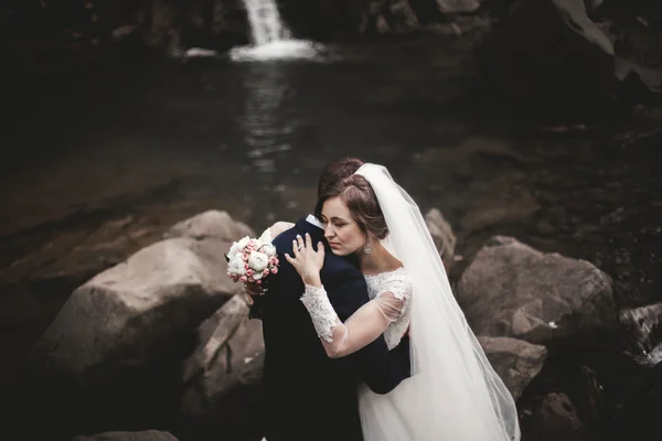 Gyönyörű esküvői pár marad a folyó festői hegyek kő — Stock Fotó