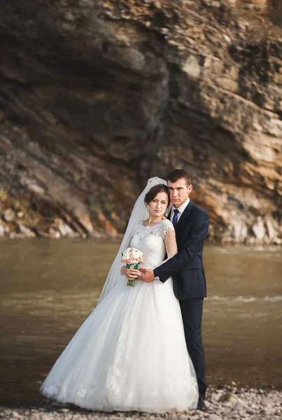 잘생긴 로맨틱 신랑과 포즈를 취하는 아름 다운 산에 강 근처 아름 다운 신부 — 스톡 사진