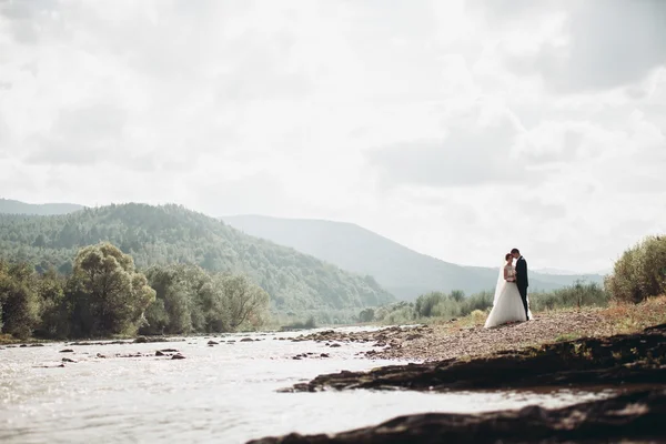 Piękny ślub para zatrzymać na kamień rzeki w malowniczych gór — Zdjęcie stockowe