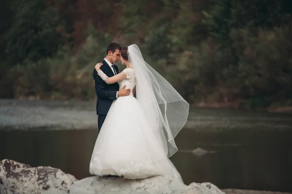 Yakışıklı romantik damat ve güzel gelin Nehri manzaralı dağlarında yakınında poz — Stok fotoğraf