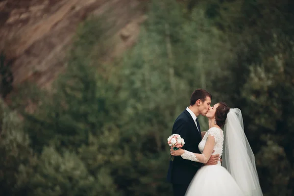 Guapo romántico novio y hermosa novia posando cerca del río en las montañas escénicas —  Fotos de Stock