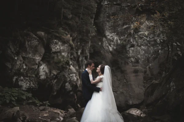 Casal bonito ficar na pedra do rio em montanhas cênicas — Fotografia de Stock