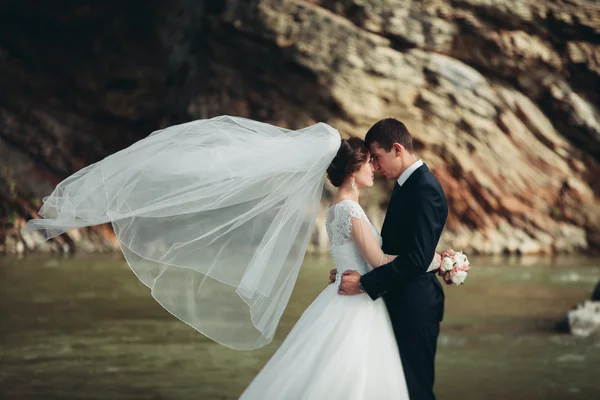 Bello sposo romantico e bella sposa in posa vicino al fiume in montagne panoramiche — Foto Stock