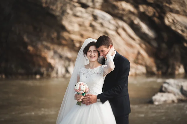 Schöner romantischer Bräutigam und schöne Braut posieren in Flussnähe in malerischen Bergen — Stockfoto