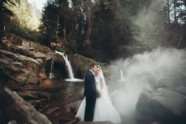 Красивая свадебная пара останавливается на камне реки в живописных горах — стоковое фото