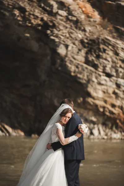 Beau marié romantique et belle mariée posant près de la rivière dans les montagnes pittoresques — Photo