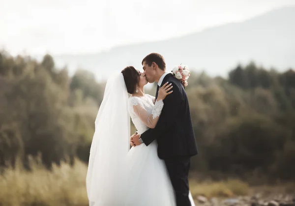 Schöner romantischer Bräutigam und schöne Braut posieren in Flussnähe in malerischen Bergen — Stockfoto